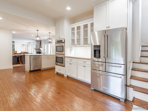 kitchen featuring stainless steel appliances, white cabinets, and hanging light fixtures