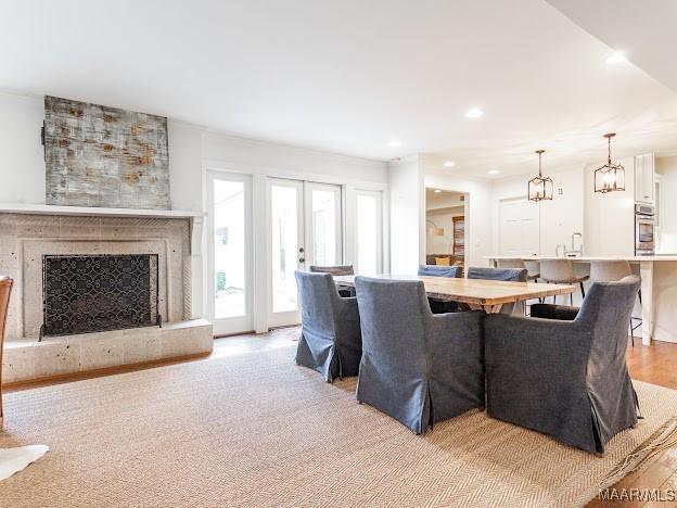 living area with recessed lighting, light wood finished floors, and a fireplace with raised hearth