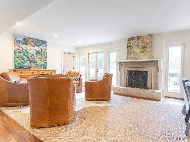 living area with recessed lighting, a fireplace with raised hearth, and wood finished floors