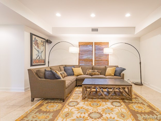 living room with a raised ceiling and light tile patterned floors