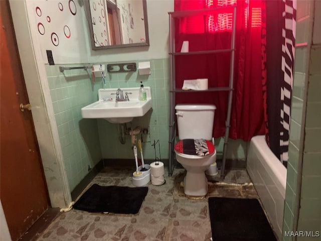 bathroom with tile walls, a wainscoted wall, and toilet