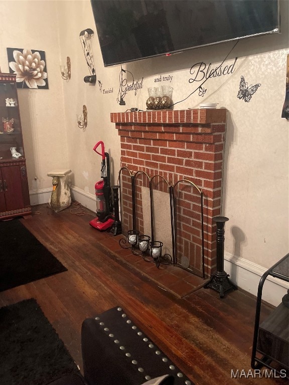 living room with a brick fireplace and wood-type flooring