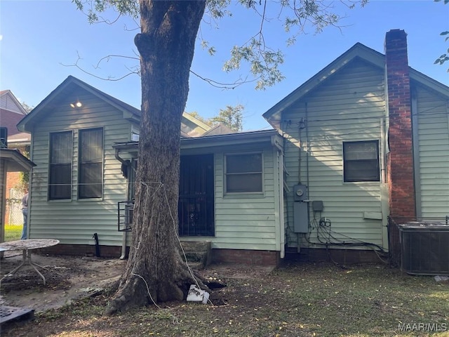 back of property featuring a chimney, entry steps, and cooling unit
