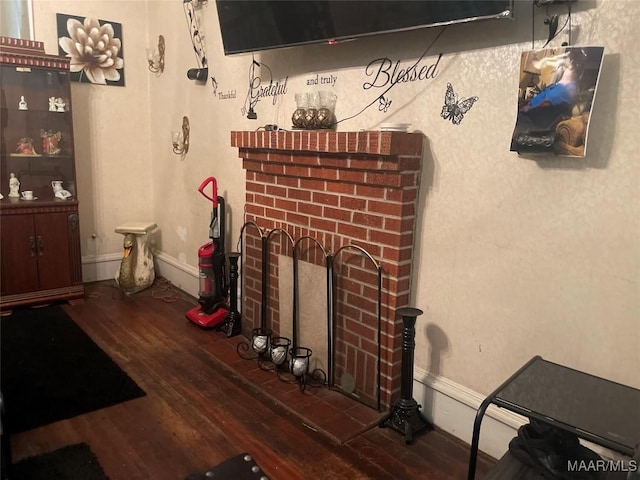 living area with a brick fireplace, hardwood / wood-style flooring, and baseboards