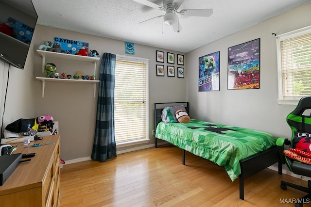 bedroom with ceiling fan, a textured ceiling, and light wood-type flooring