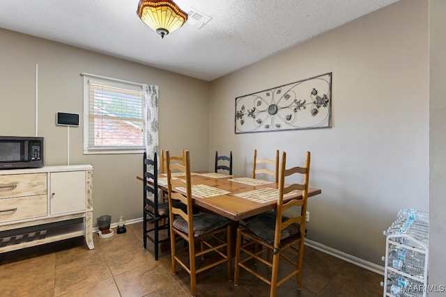 tiled dining room with a textured ceiling