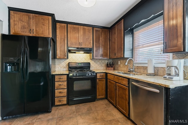 kitchen with sink, light stone counters, backsplash, a textured ceiling, and black appliances