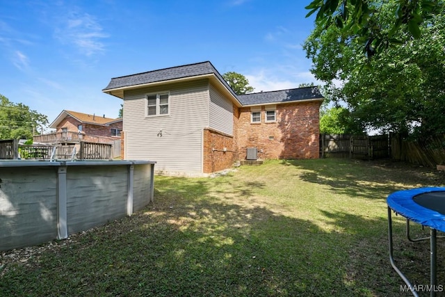 view of yard with a trampoline and central air condition unit