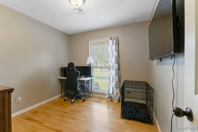 office with light hardwood / wood-style floors and a textured ceiling