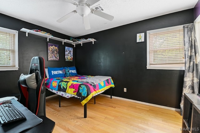 bedroom with wood-type flooring, multiple windows, and ceiling fan