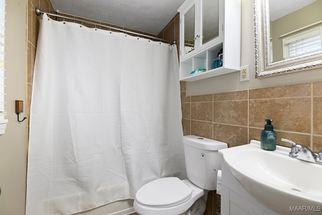 full bathroom with a textured ceiling, vanity, toilet, and tile walls