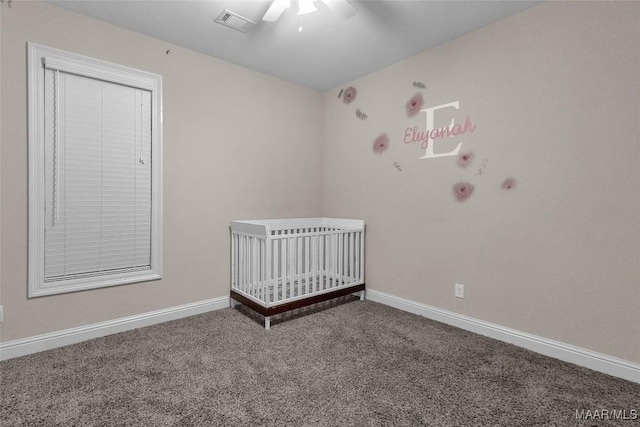 unfurnished bedroom featuring carpet, a crib, and ceiling fan