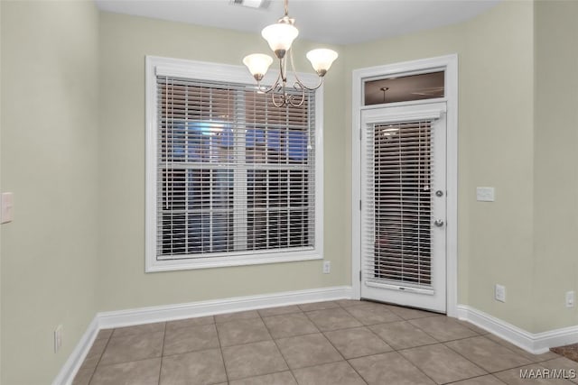 unfurnished dining area featuring an inviting chandelier and light tile patterned flooring