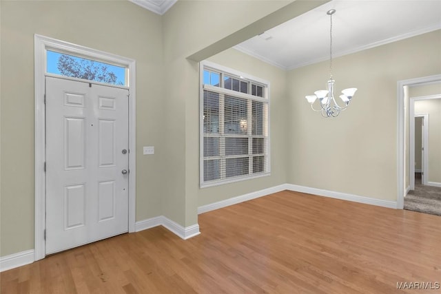 foyer entrance featuring light hardwood / wood-style floors, ornamental molding, and a notable chandelier