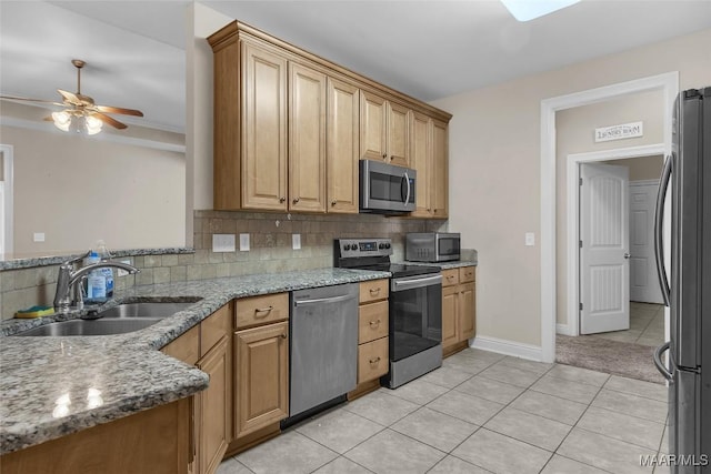 kitchen with stone counters, sink, ceiling fan, light tile patterned flooring, and stainless steel appliances