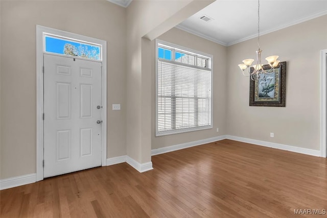 entrance foyer featuring hardwood / wood-style floors, crown molding, and an inviting chandelier