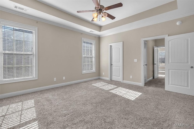 unfurnished bedroom with carpet, ceiling fan, crown molding, and a tray ceiling