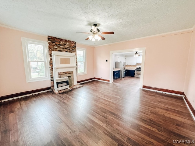 unfurnished living room featuring ceiling fan, a brick fireplace, dark wood-type flooring, and a wealth of natural light