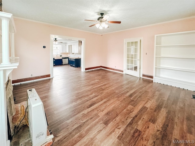 unfurnished living room featuring ceiling fan, wood-type flooring, a fireplace, ornamental molding, and a textured ceiling