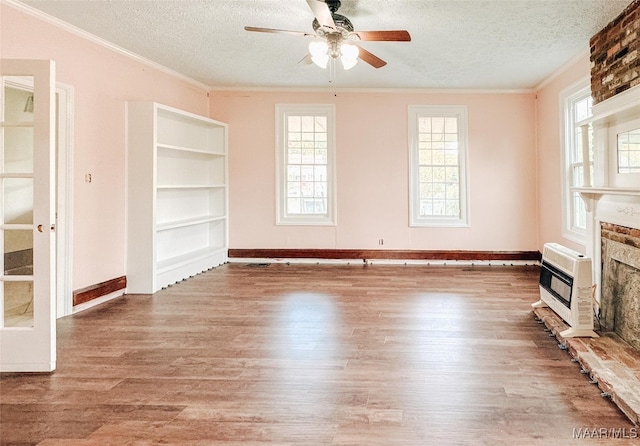 unfurnished living room featuring a fireplace, wood-type flooring, heating unit, and a textured ceiling