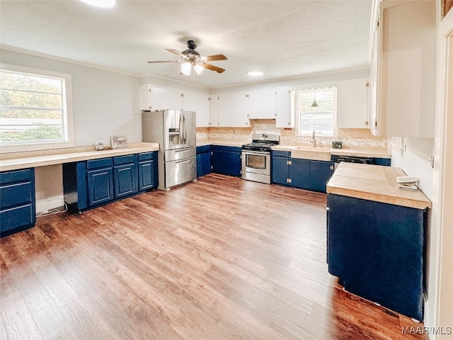 kitchen with white cabinets, appliances with stainless steel finishes, light wood-type flooring, and a healthy amount of sunlight