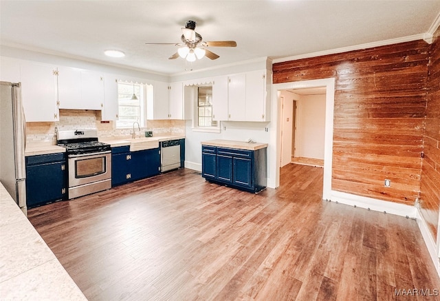 kitchen featuring wood walls, white cabinets, appliances with stainless steel finishes, and blue cabinetry