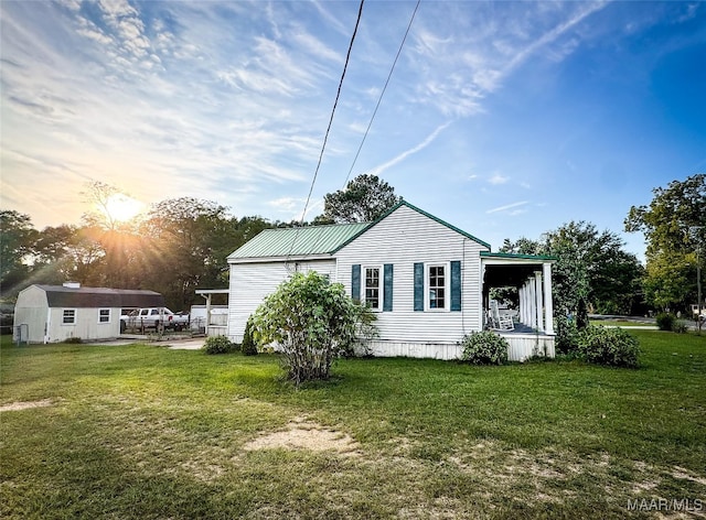 property exterior at dusk featuring a storage shed and a lawn