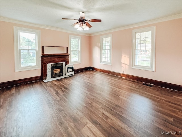 unfurnished living room with heating unit, dark hardwood / wood-style flooring, ornamental molding, and a healthy amount of sunlight