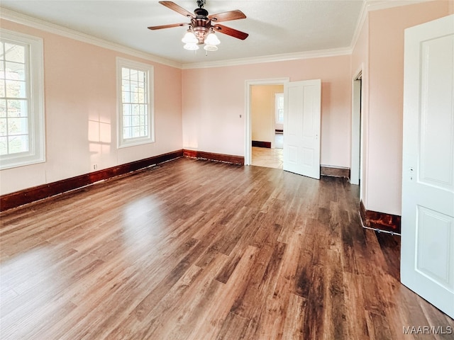 empty room featuring ceiling fan, dark hardwood / wood-style floors, crown molding, and a healthy amount of sunlight