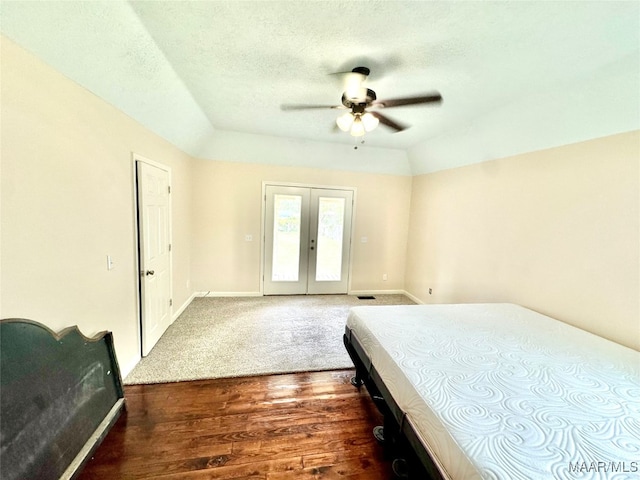 bedroom featuring ceiling fan, dark wood-type flooring, lofted ceiling, french doors, and a textured ceiling