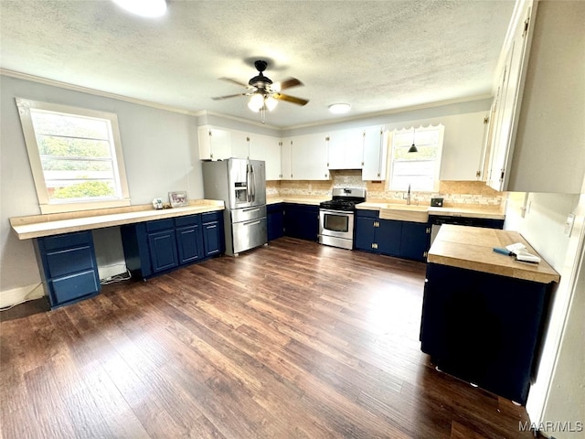 kitchen with blue cabinets, backsplash, dark hardwood / wood-style floors, white cabinets, and appliances with stainless steel finishes