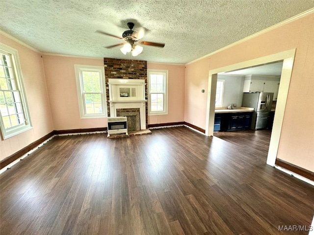 unfurnished living room with ornamental molding, a brick fireplace, heating unit, a textured ceiling, and dark hardwood / wood-style floors