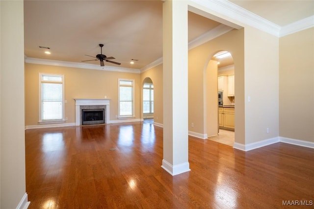 unfurnished living room featuring ceiling fan, light hardwood / wood-style floors, ornamental molding, and a fireplace