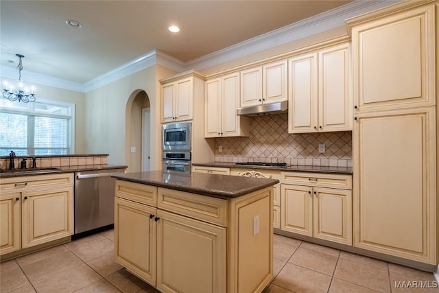 kitchen with a center island, cream cabinets, sink, appliances with stainless steel finishes, and decorative light fixtures