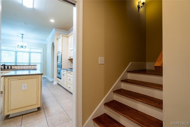 stairway with tile patterned flooring, a notable chandelier, and ornamental molding