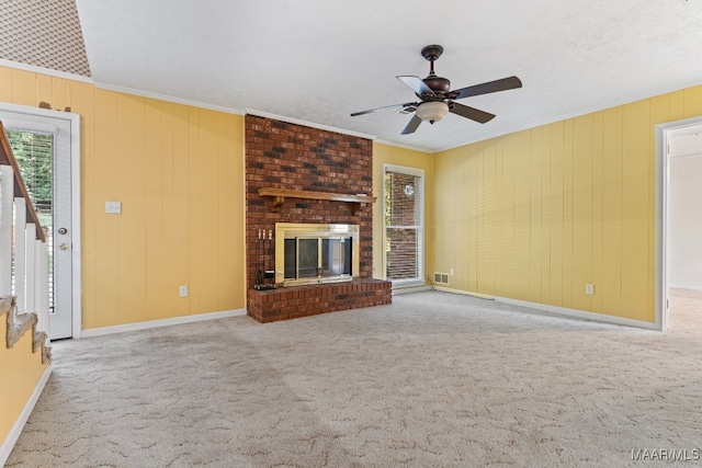 unfurnished living room featuring ceiling fan, carpet floors, crown molding, and a fireplace