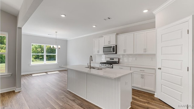 kitchen with hardwood / wood-style flooring, white cabinets, an island with sink, and appliances with stainless steel finishes