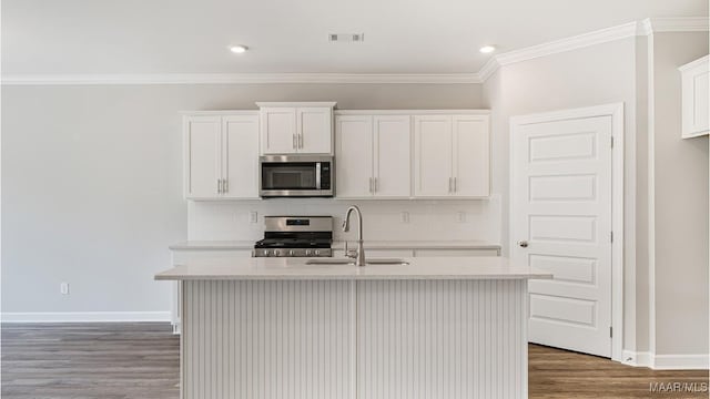 kitchen with white cabinets, sink, appliances with stainless steel finishes, and an island with sink