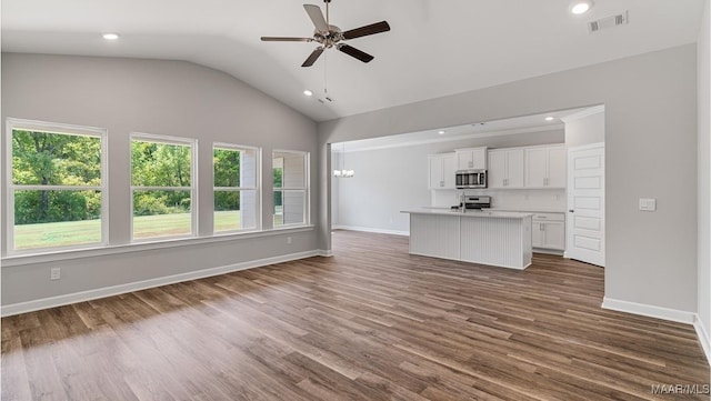 unfurnished living room with vaulted ceiling, ceiling fan with notable chandelier, and dark hardwood / wood-style floors