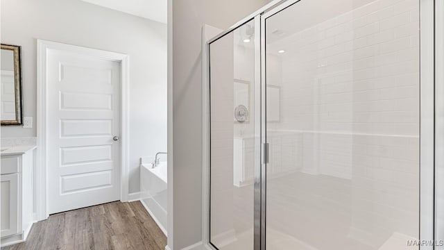 bathroom with hardwood / wood-style floors, vanity, and shower with separate bathtub