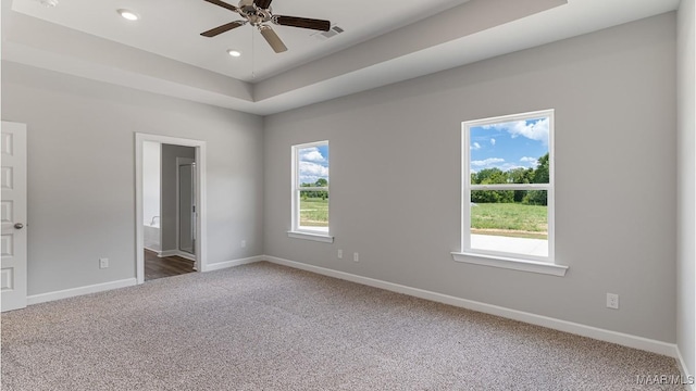 spare room featuring carpet flooring, ceiling fan, and a tray ceiling