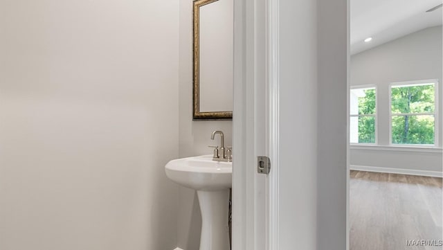 bathroom with wood-type flooring, sink, and vaulted ceiling