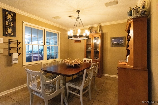 dining area with ornamental molding, an inviting chandelier, and dark tile patterned flooring