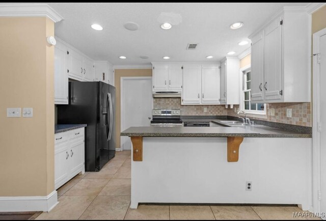 3033 Willow Lane Dr, Montgomery, AL 36109 - kitchen with stainless steel range with electric stovetop, black fridge, under cabinet range hood, a peninsula, and dark countertops