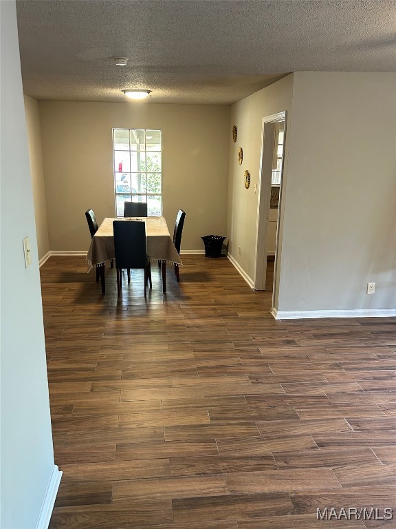 dining room featuring a textured ceiling and dark hardwood / wood-style flooring