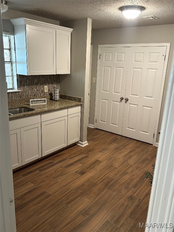 kitchen featuring white cabinets, a textured ceiling, and dark wood-type flooring