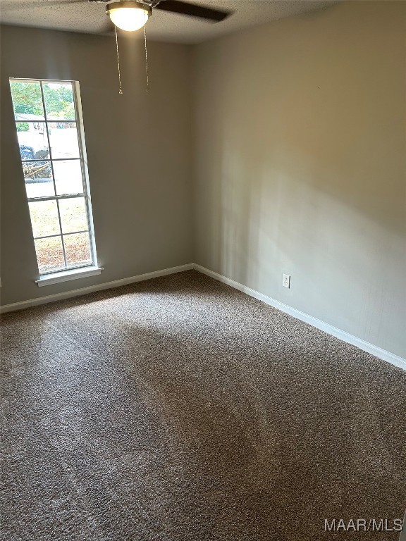 carpeted empty room with ceiling fan, a textured ceiling, and a healthy amount of sunlight