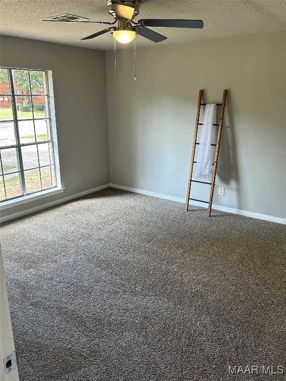 carpeted empty room featuring ceiling fan and a textured ceiling