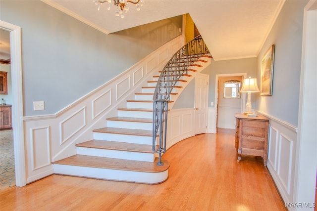 stairs with a notable chandelier, crown molding, and hardwood / wood-style floors