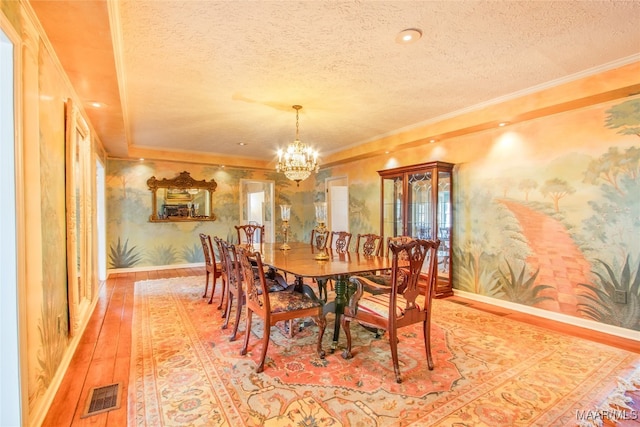 dining area featuring a textured ceiling, crown molding, a chandelier, and hardwood / wood-style flooring